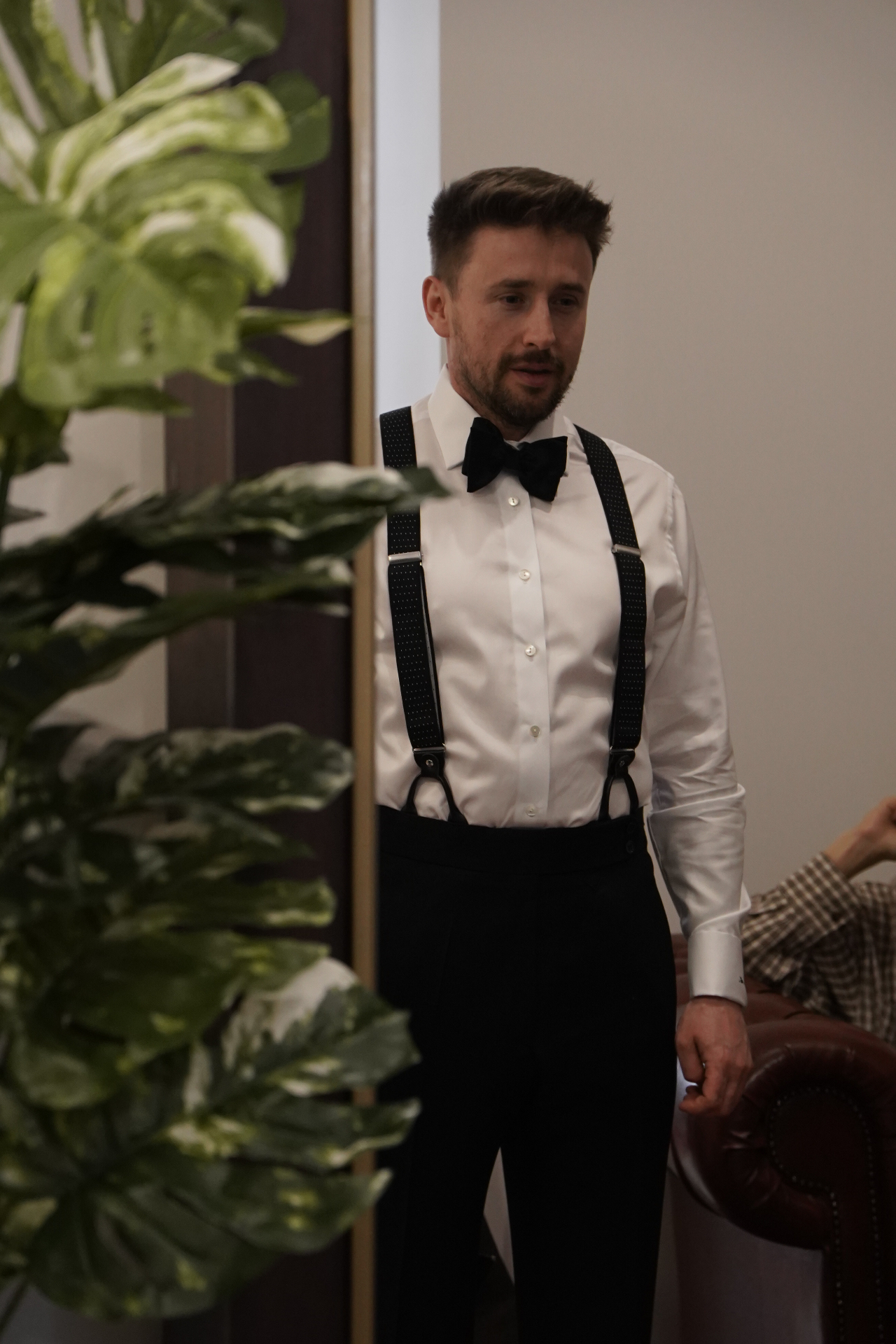Klient w białej koszuli z muszką i szelkami - przymiarka smokingu